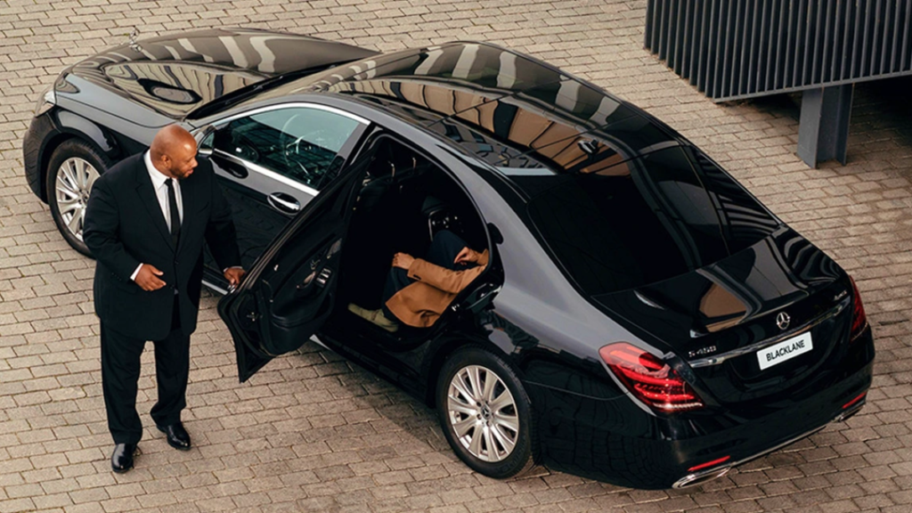 Chauffeur holding the door of a black sedan